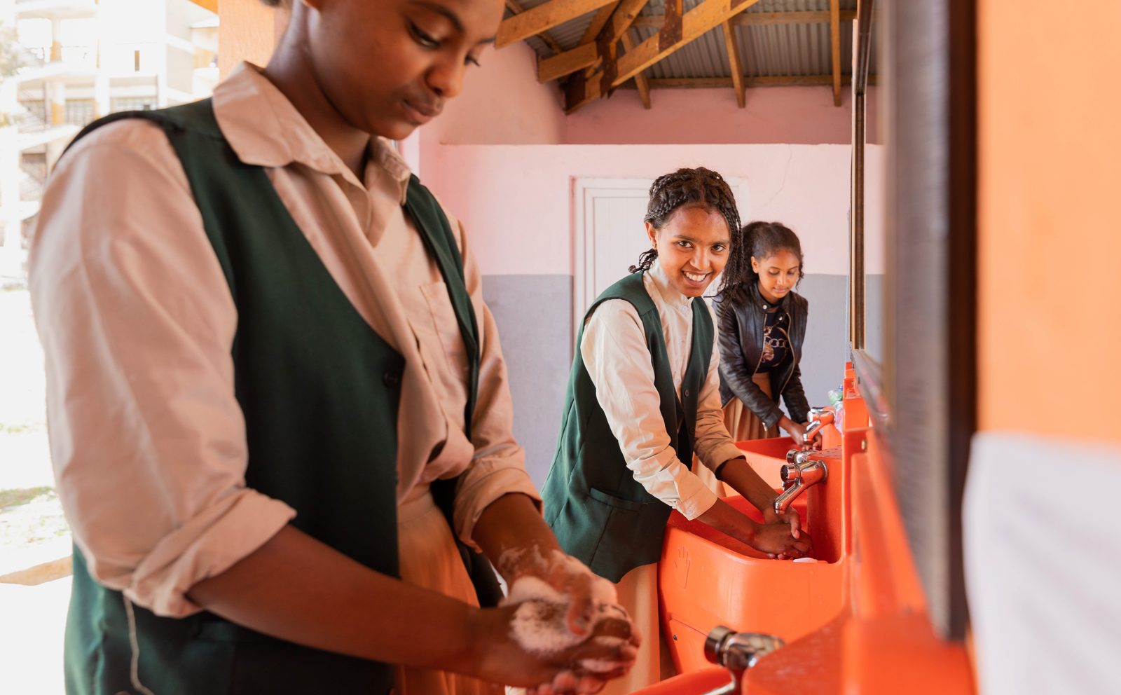 Students washing their hands with soap at an orange Splash handwashing station